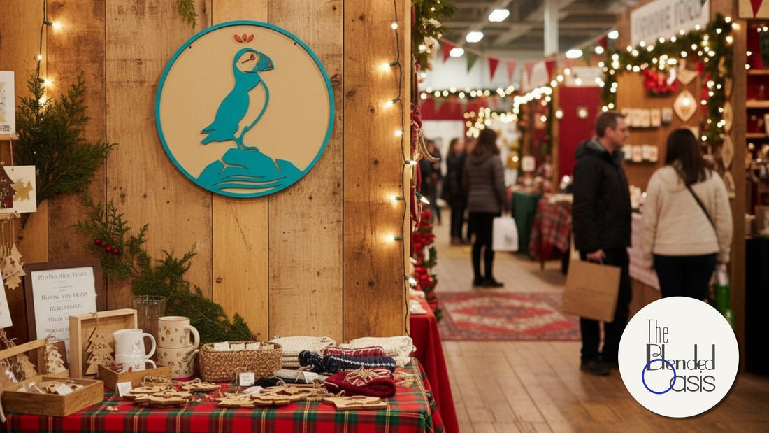 A festive and rustic indoor holiday market stall, decorated with string lights and greenery, showcasing artisan crafts on a plaid tablecloth, with a prominent circular sign featuring a teal puffin design.