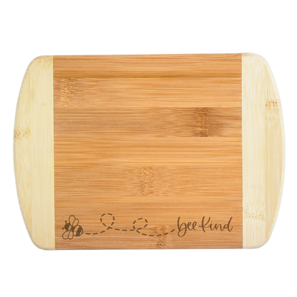 Bamboo cutting board with 'bee kind' engraving on a white background