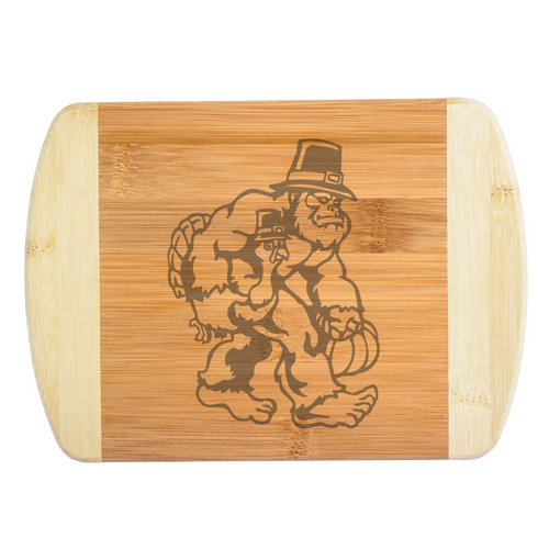 A premium engraved bamboo cutting board featuring a funny autumn illustration of Bigfoot wearing a buckled hat while carrying a turkey and a pumpkin, handcrafted by The Blended Oasis in Washington State.