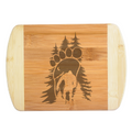 A premium engraved bamboo cutting board featuring an intricate illustration of a giant footprint framed by pine trees and filled with a crescent moon, starry night sky, mountains, and a walking Bigfoot silhouette, handcrafted by The Blended Oasis in Washington State.