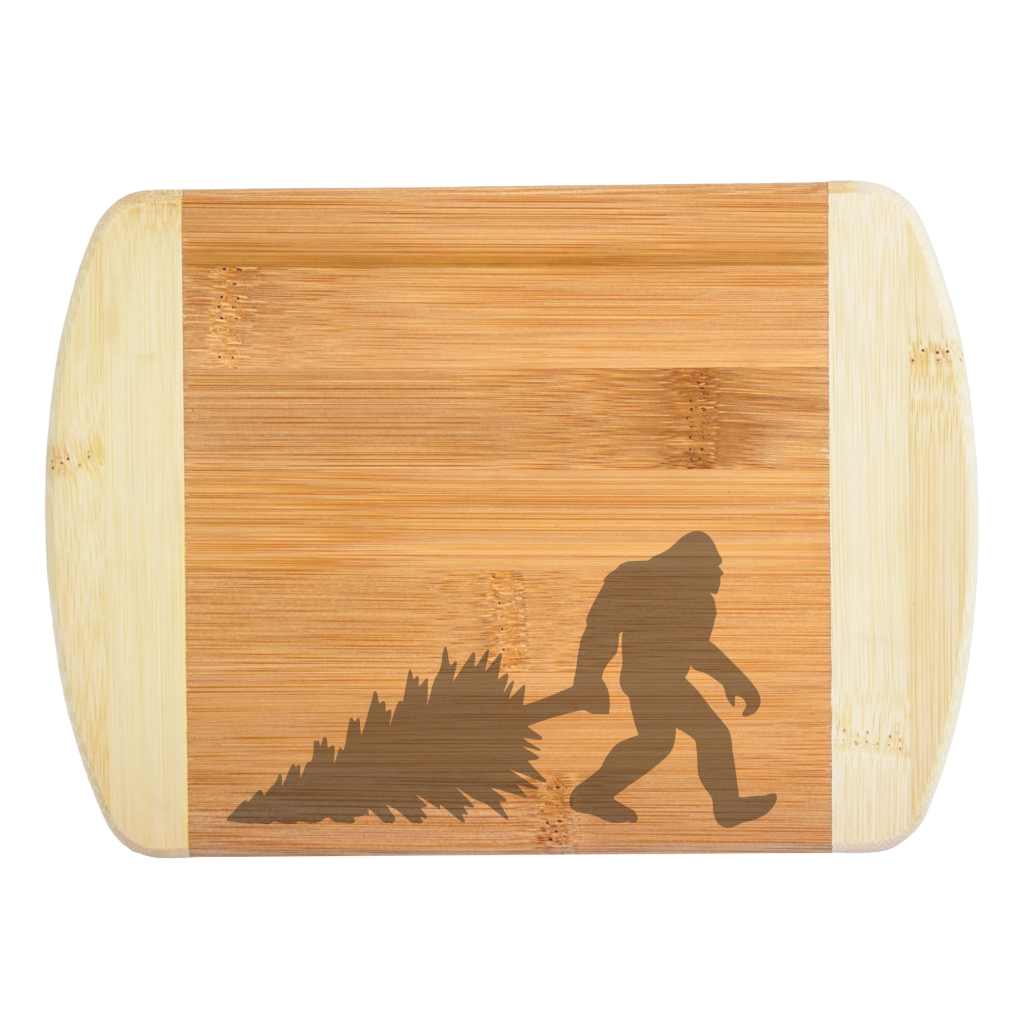 A premium engraved bamboo cutting board featuring a funny, low-profile corner illustration of Bigfoot dragging a pine tree, handcrafted by The Blended Oasis in Washington State.