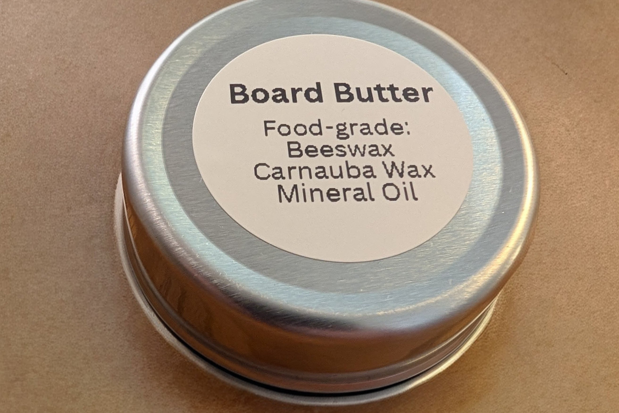 Tin of Board Butter with a label on a brown background