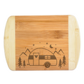 Laser engraved bamboo cutting board with a custom design featuring a classic raindrop camper, pine evergreen trees, mountain, moon, stars. Cutting board is on a white background. 