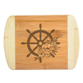An elegant laser-engraved bamboo cutting board featuring a detailed nautical ship wheel accented with a beautiful bouquet of blooming flowers, handcrafted by The Blended Oasis in Washington State.