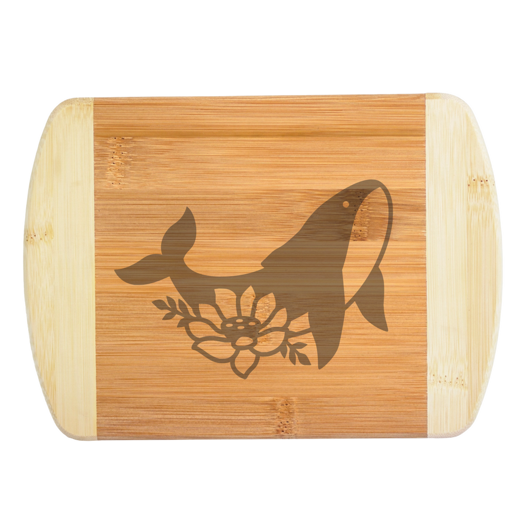 An elegant engraved bamboo cutting board featuring a unique artistic design of a whale silhouette paired with a blooming lotus flower, handcrafted by The Blended Oasis in Washington State.