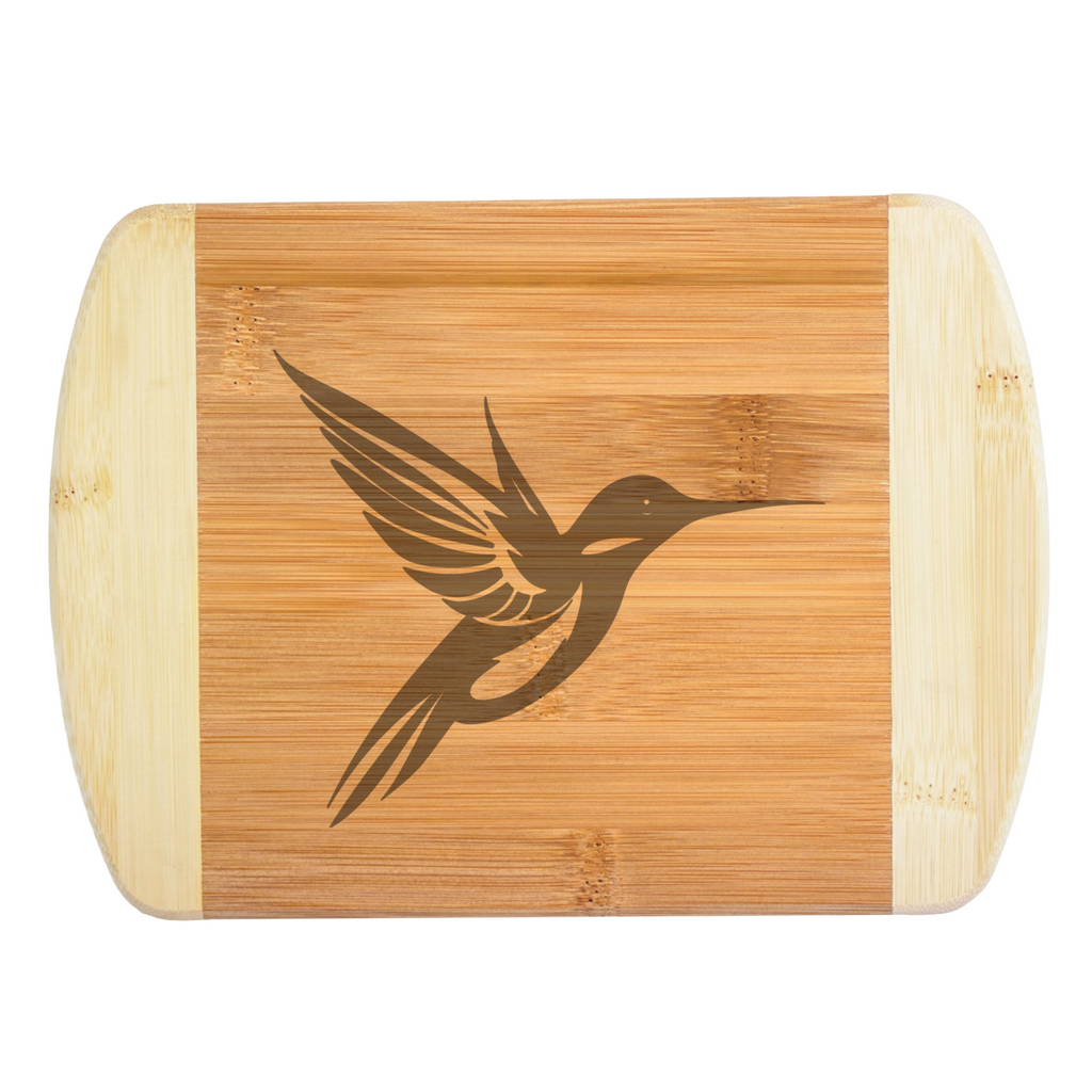 A premium engraved bamboo cutting board featuring a sleek, stylized modern illustration of a hummingbird with bold geometric wings, handcrafted by The Blended Oasis in Washington State.