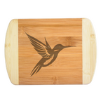 A premium engraved bamboo cutting board featuring a sleek, stylized modern illustration of a hummingbird with bold geometric wings, handcrafted by The Blended Oasis in Washington State.