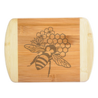 A premium engraved bamboo cutting board featuring a unique honeybee design layered with geometric honeycomb shapes and garden flowers, handcrafted by The Blended Oasis in Washington State.