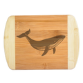 A premium engraved bamboo cutting board showcasing a detailed modern illustration of a swimming humpback whale silhouette, handcrafted by The Blended Oasis in Washington State.