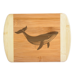 A premium engraved bamboo cutting board showcasing a detailed modern illustration of a swimming humpback whale silhouette, handcrafted by The Blended Oasis in Washington State.