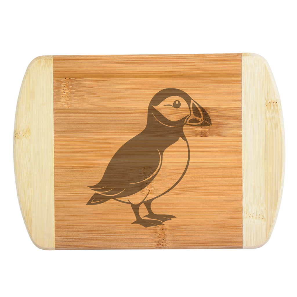 A premium engraved bamboo cutting board featuring a sleek, minimalist modern illustration of a puffin bird silhouette, handcrafted by The Blended Oasis in Washington State.