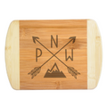 A premium engraved bamboo cutting board featuring a trendy modern illustration of crossed arrows with the letters PNW and a clean mountain peak silhouette, handcrafted by The Blended Oasis in Washington State.