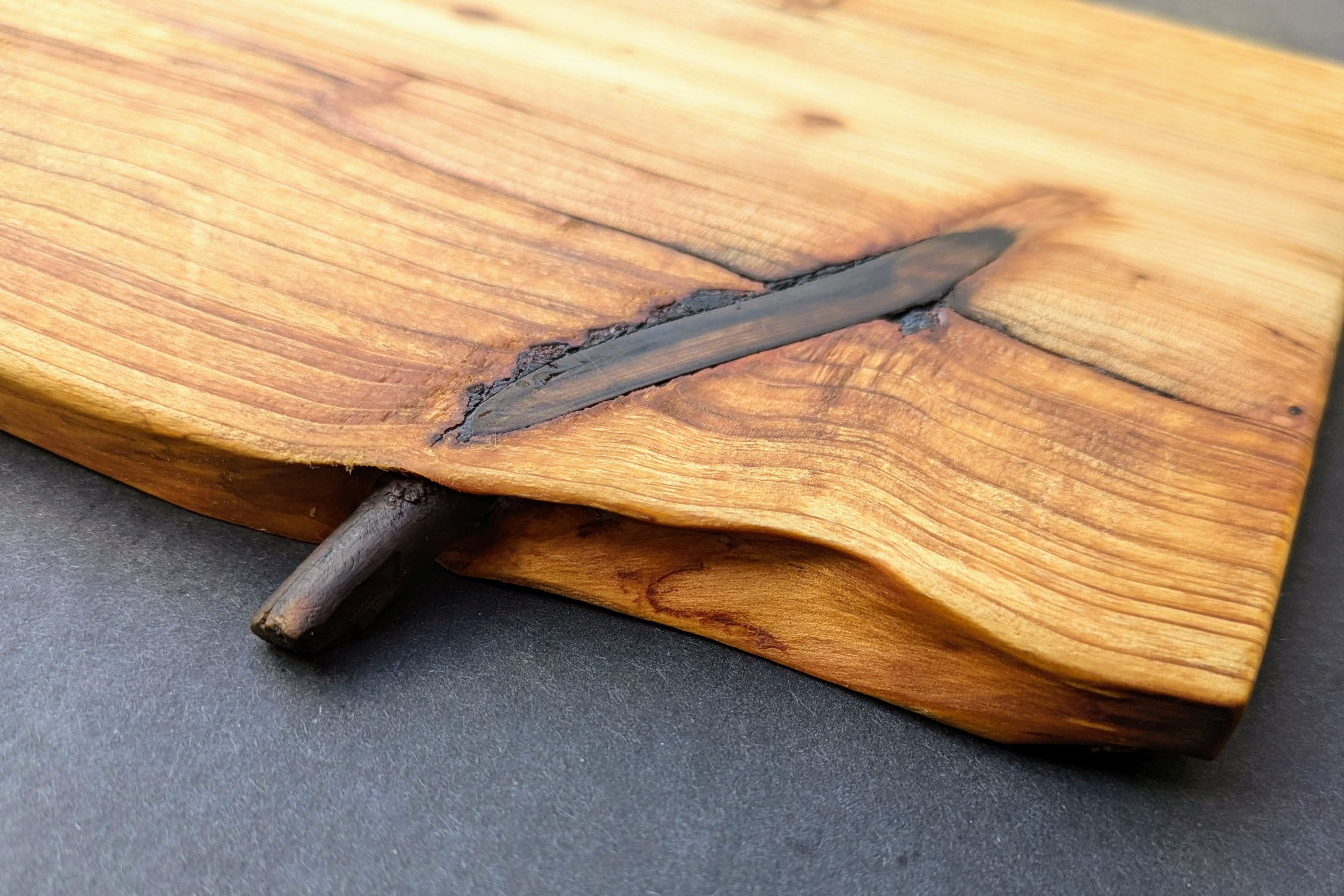 Wooden cutting board with natural edge 
on a gray surface