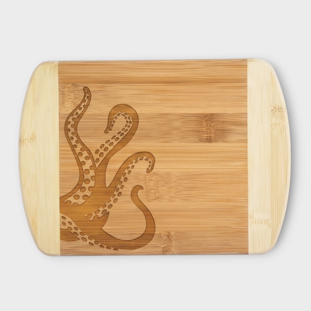 A rectangular bamboo cutting board with rounded corners and light natural wood handles, featuring a dark brown engraved octopus design on the front, set against a solid light gray background.