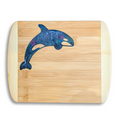 A top-down studio product photo by The Blended Oasis in Suquamish, WA, showcasing a handcrafted bamboo cutting board with a vibrant epoxy resin inlay of a breaching orca killer whale. The resin features a deep, metallic cosmic swirl of deep blue, shimmering teal, and hints of purple. Set cleanly against a solid white background with a soft drop shadow.