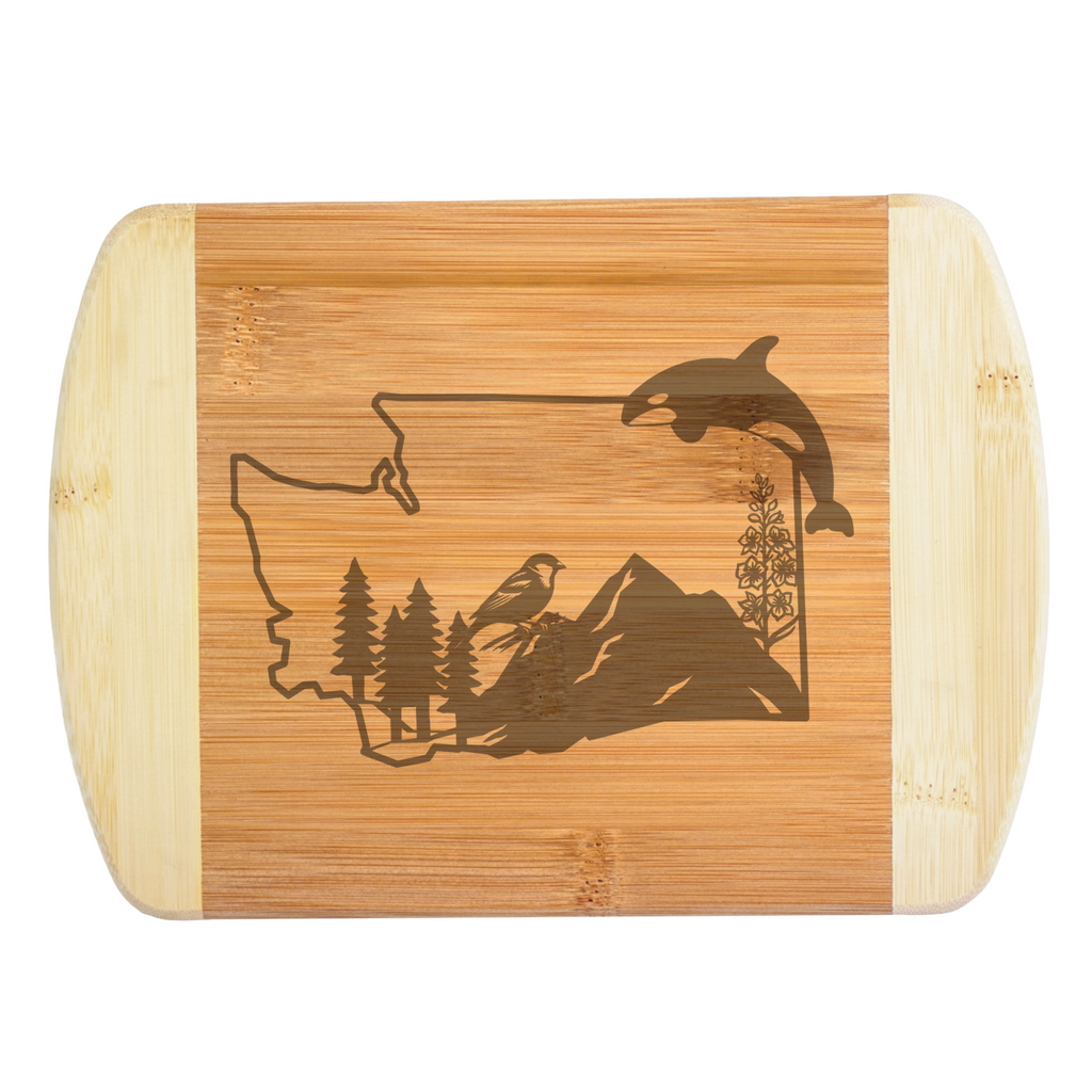 A premium engraved bamboo cutting board featuring an intricate design of Washington State filled with mountains, evergreen trees, a sparrow, a wildflower, and a leaping orca whale, handcrafted by The Blended Oasis in Washington State.